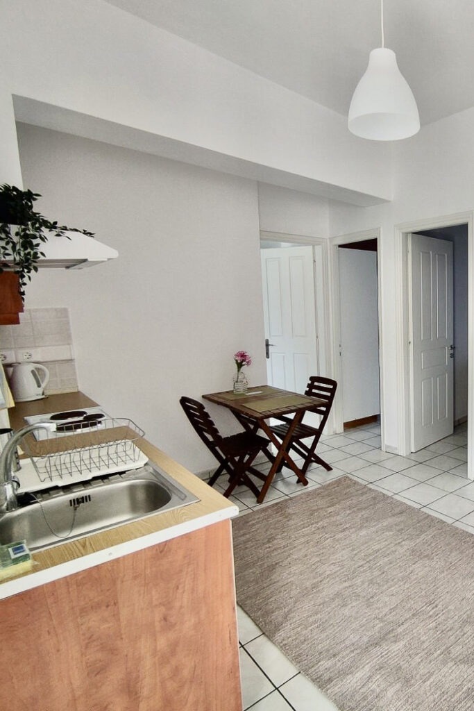 The kitchen area of Galatea living room. There's a kitchenette and a small brown table with two chairs.