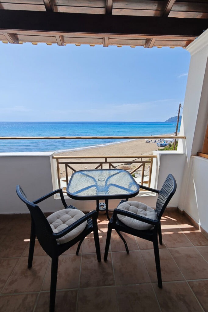 Glafki's balcony with a table and two chairs and beach view of Agios Gordios.