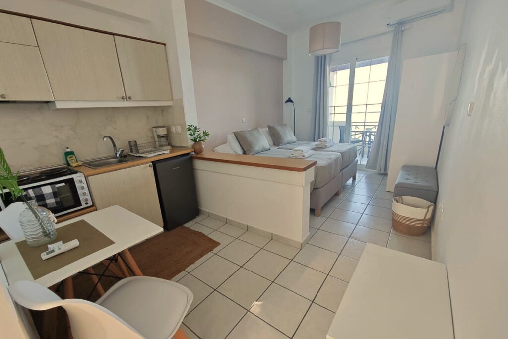 The kitchen area in Glafki studio with a small table and two chairs. Two single large beds next to each other are in the background.
