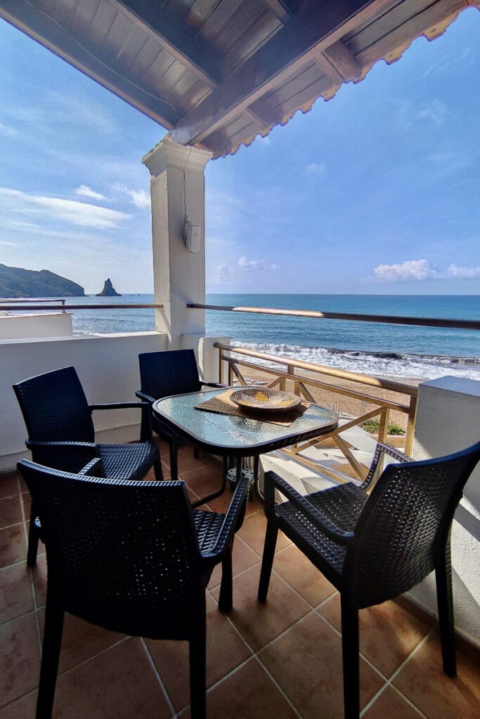 The balcony with a table and four chairs of Pasithea apartment with sea view of Agios Gordios Beach.