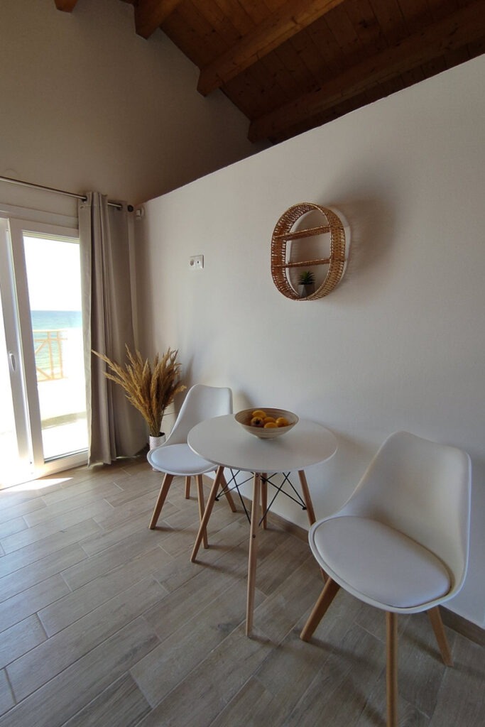 A round white table with two chairs in Nemertes' living room. The wall behind the wall doesn't reach the roof.