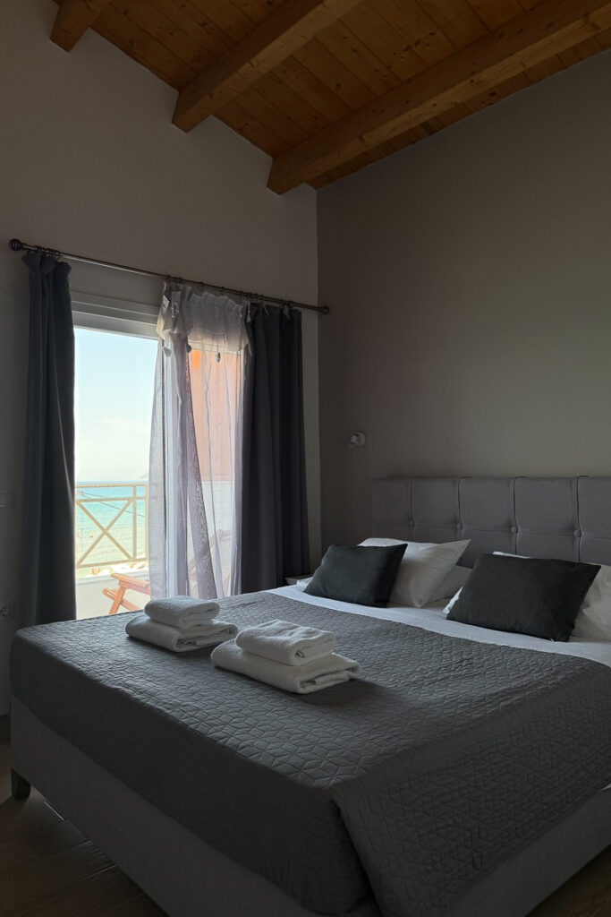 Nemertes' bedroom equipped with a double bed with grey linen and fresh white towels on top.